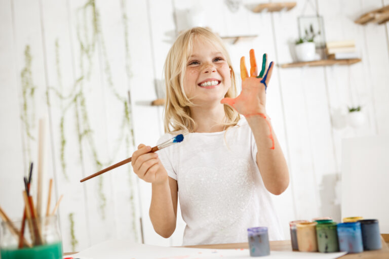 happy blond girl holding a paint brush | Kids Paint Parties | Merely Creative, Martinsburg WV